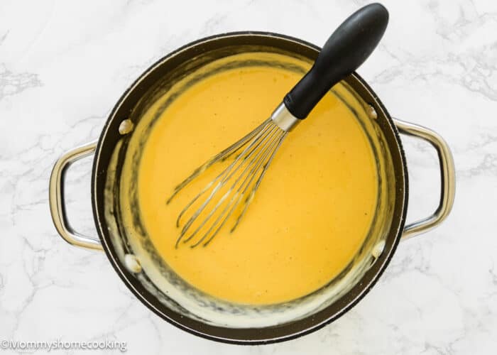 cheese sauce to make mac and cheese in a sauce pan with a whisk.