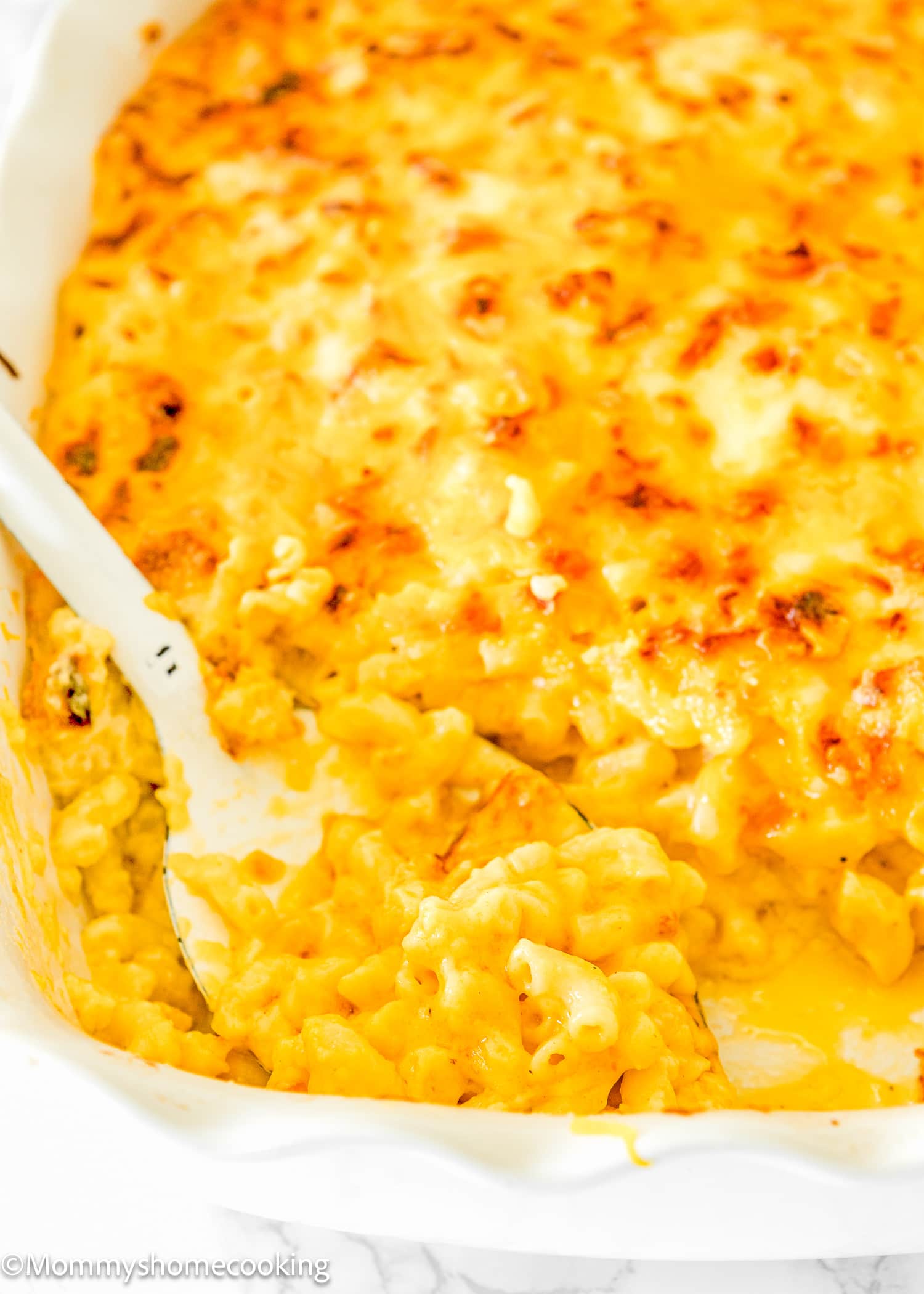 a serving spoon with the cremiest baked mac and cheese ever!