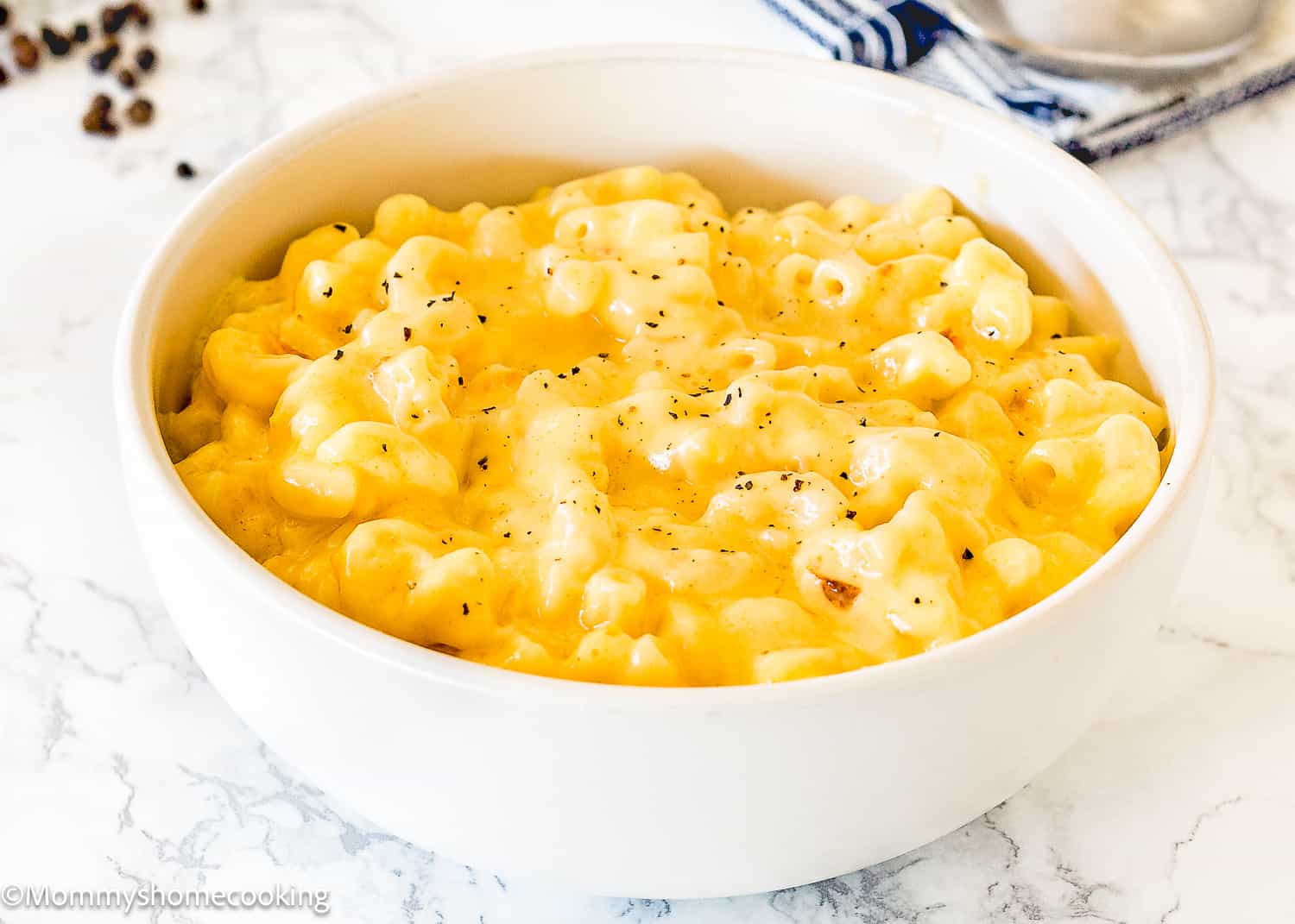 cremiest baked mac and cheese in a bowl sprinkled with pepper.