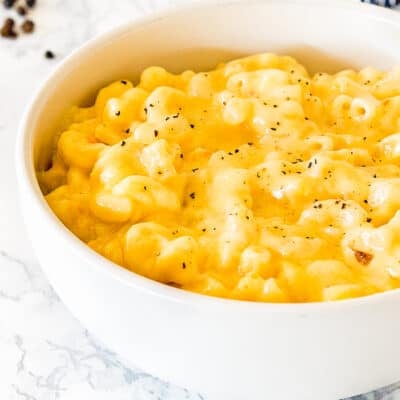 cremiest baked mac and cheese in a bowl sprinkled with pepper over a marble surface.