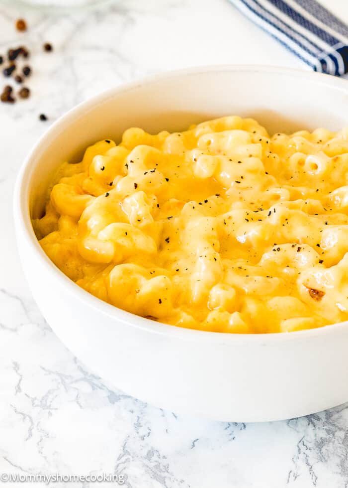 cremiest baked mac and cheese in a bowl sprinkled with pepper over a marble surface.
