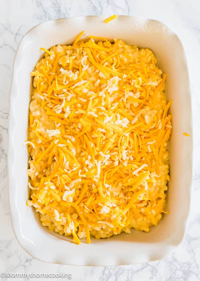 a baking dish with one layer of mac and cheese topped with more cheese.