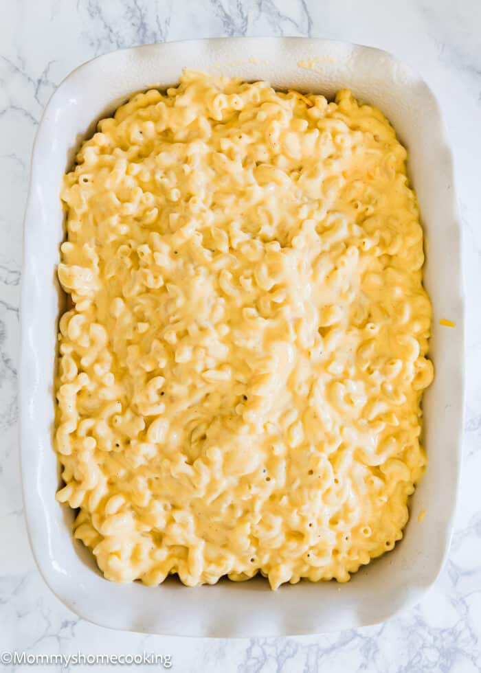 a baking dish with one layer of mac and cheese topped with more cheese, and another layer of mac and cheese.