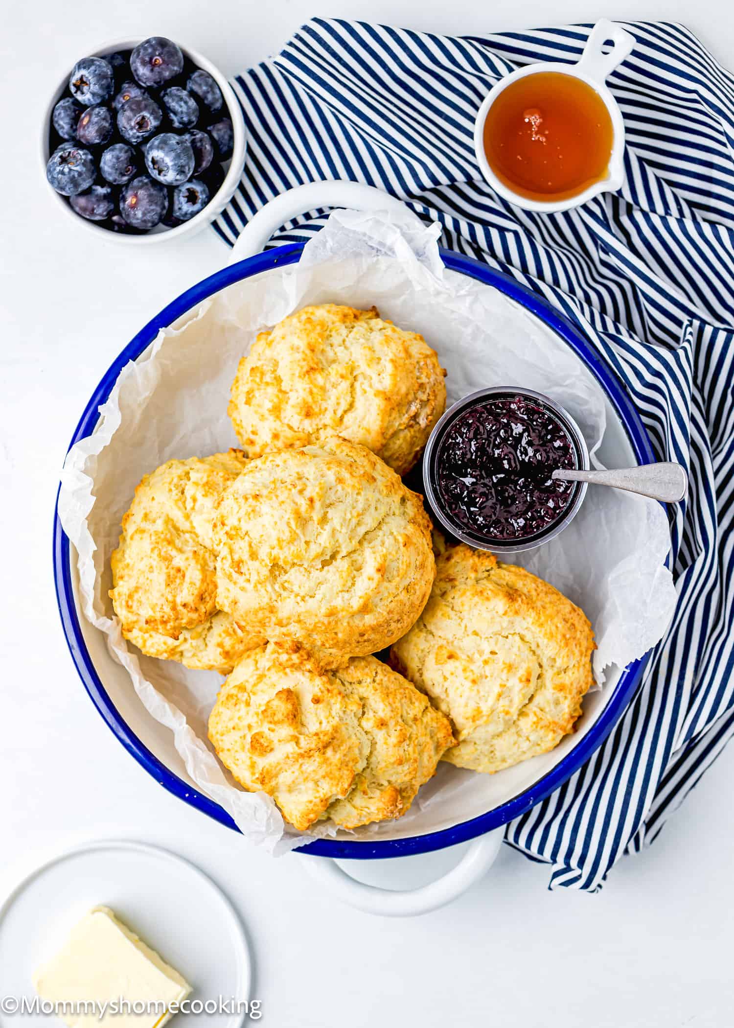 homemade Drop Biscuits in a serving plate with jam and fresh blueberries, honey and butter on the side.