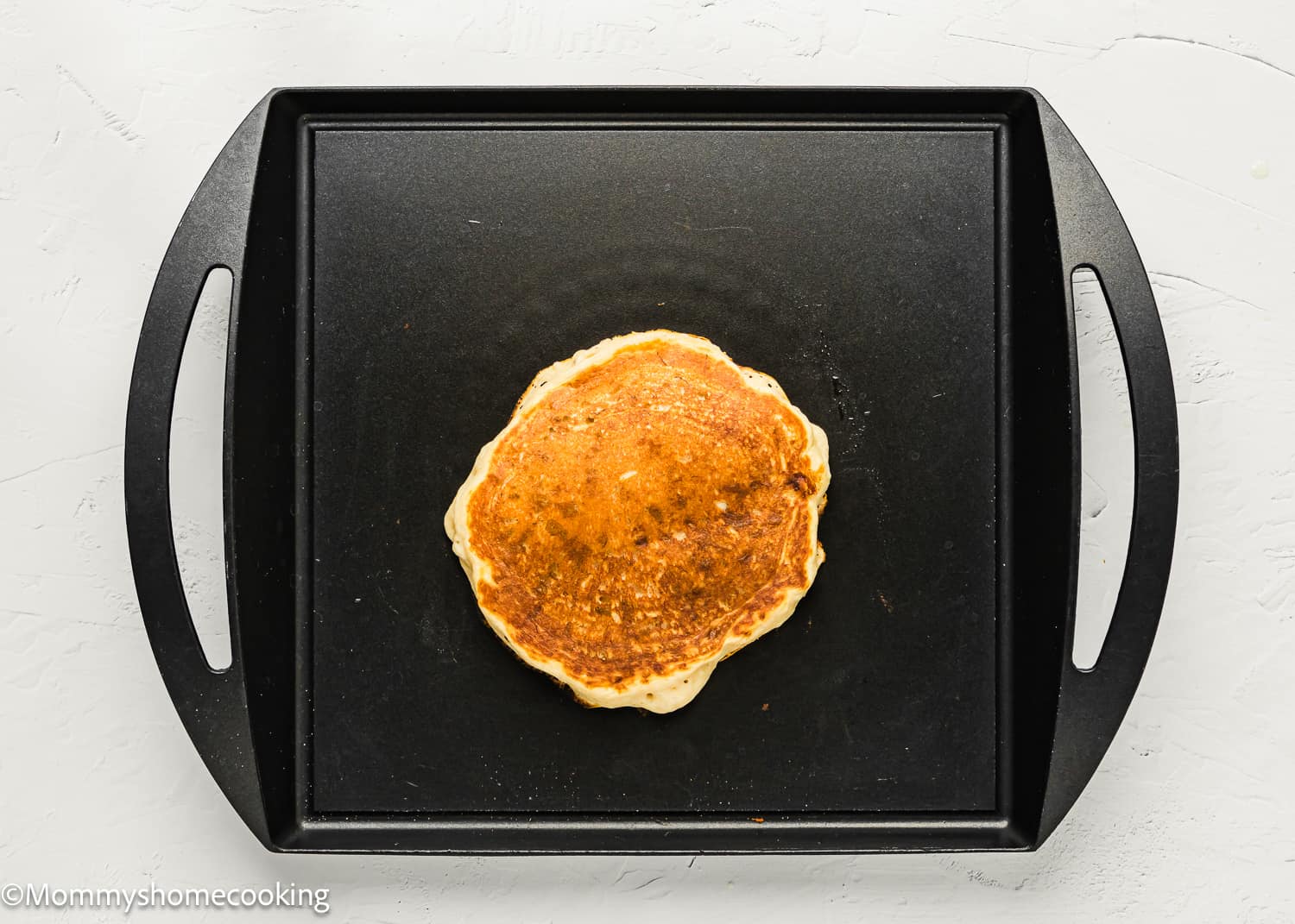 an eggless Banana Pancake being cooked in a griddle.