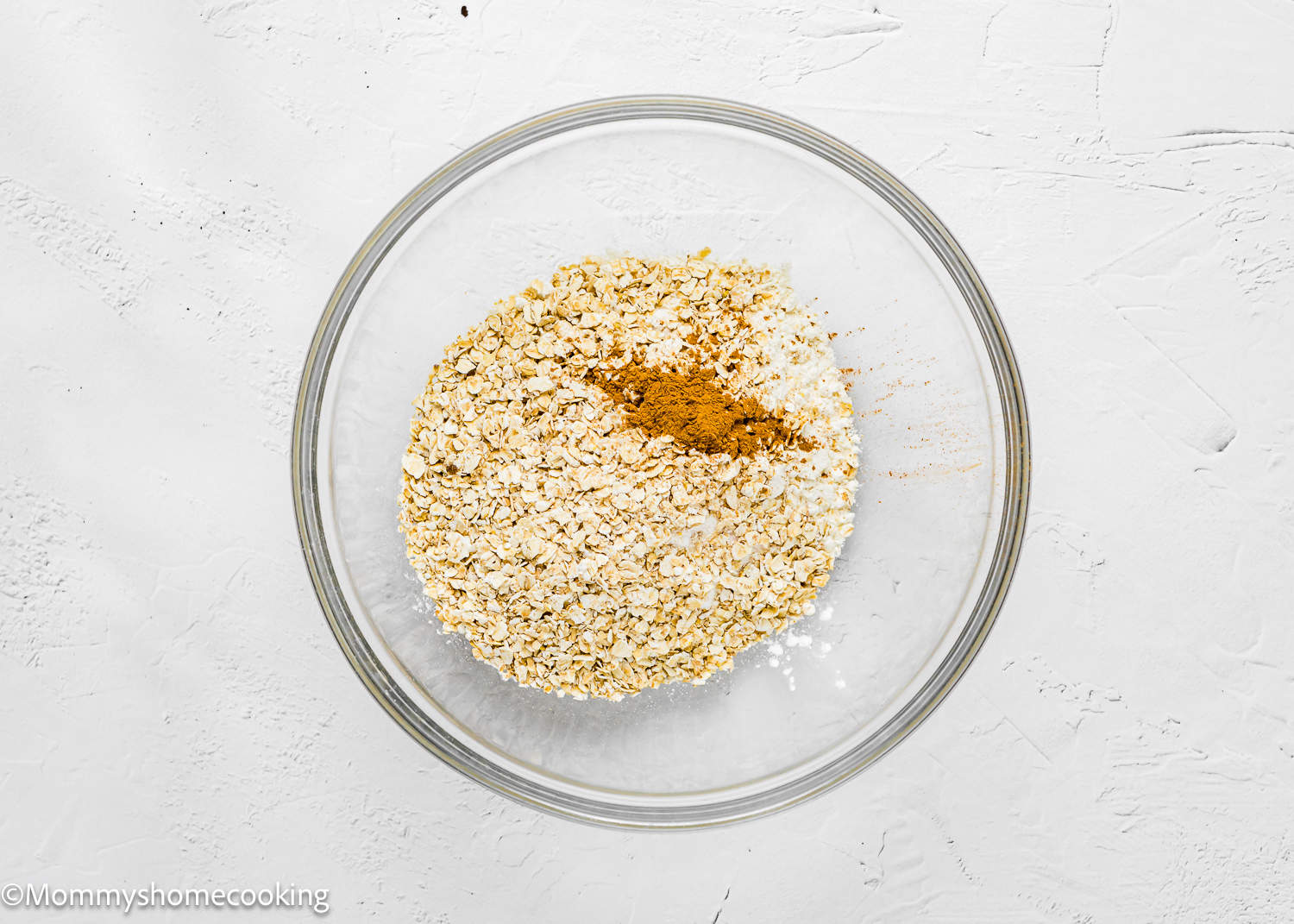 Healthy oats, flour, and aromatic cinnamon in a glass bowl to make healthy oat muffins.