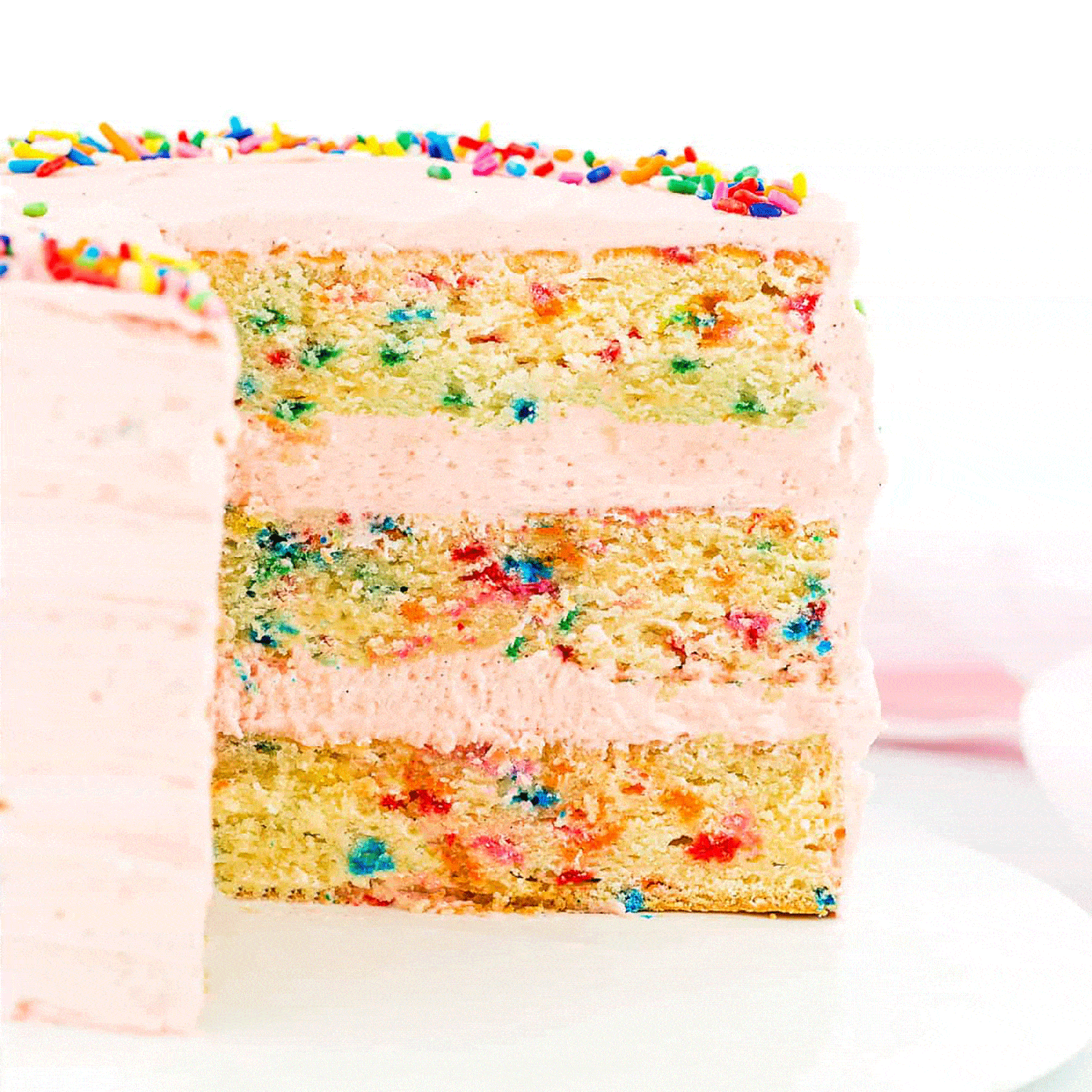 sliced eggless funfetti layer cake on a white plate.
