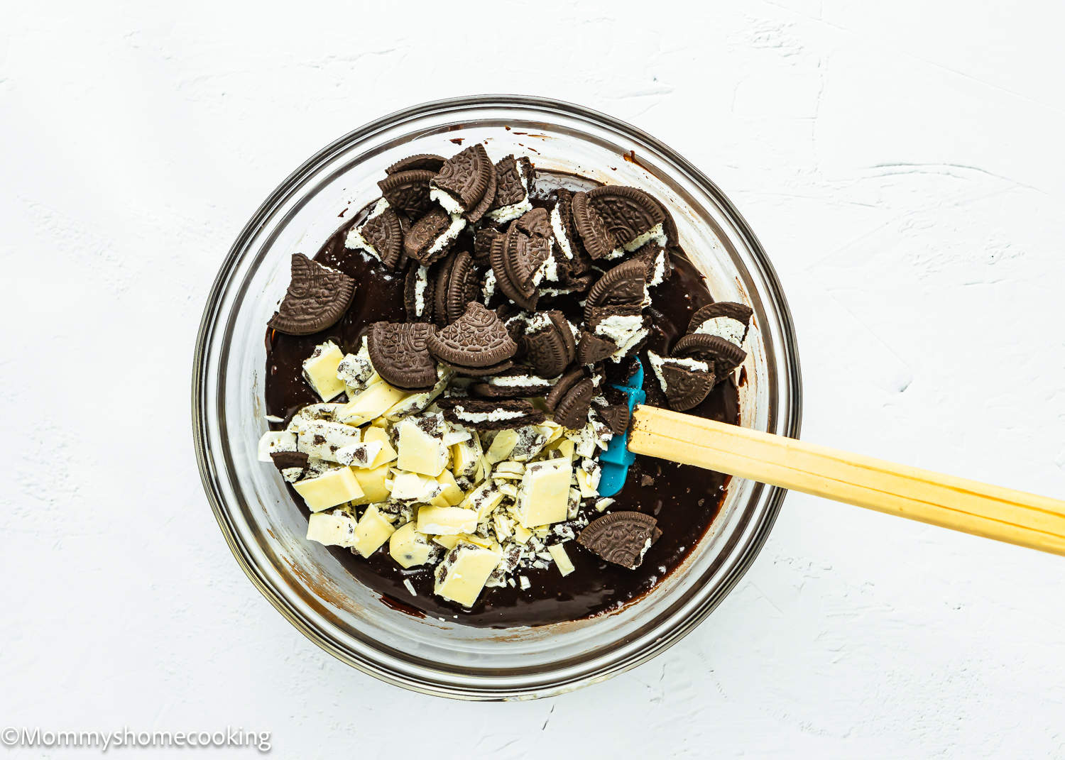 Oreo cookie brownie batter in a bowl with a wooden spoon.