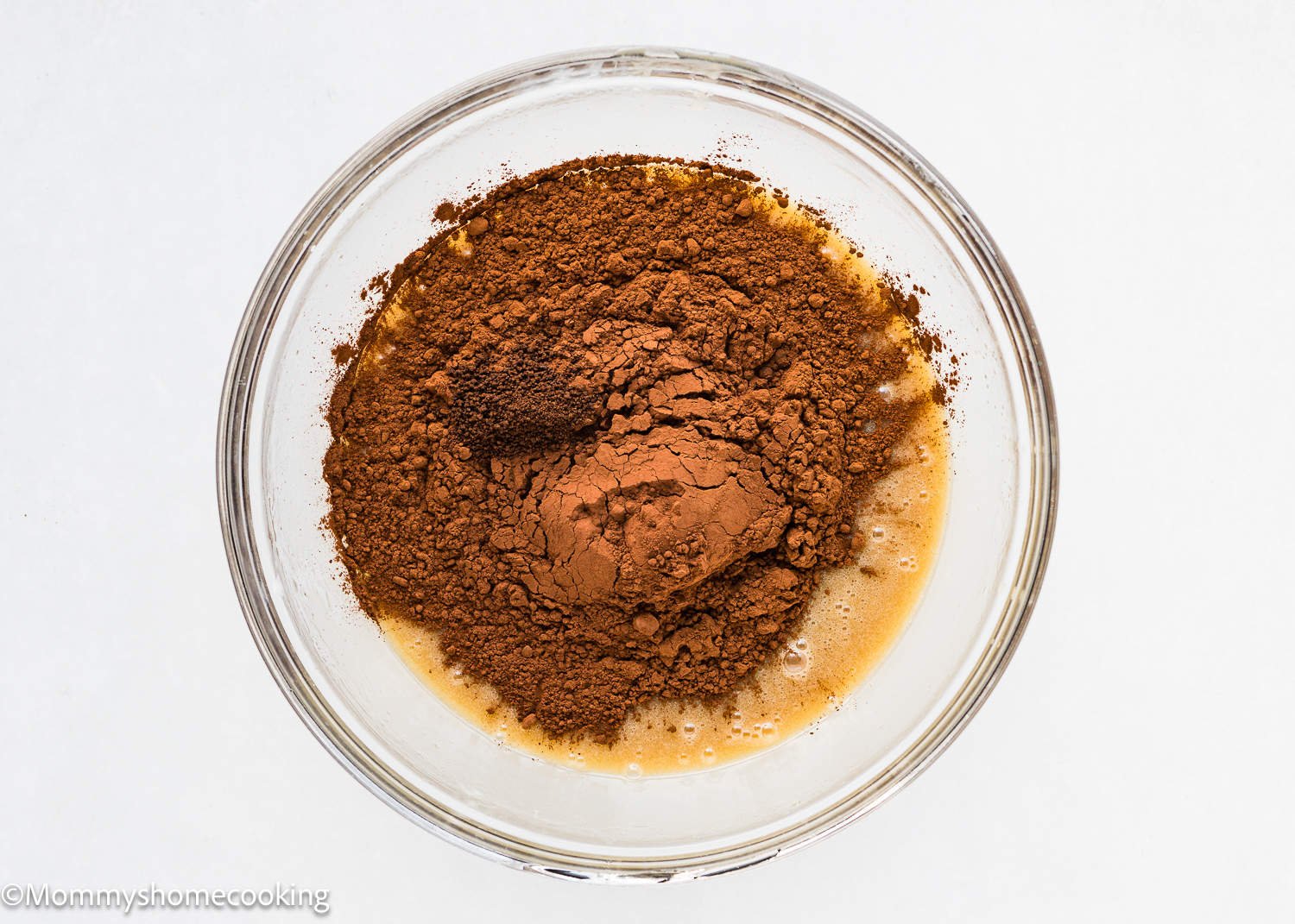 wet ingredients to make egg-free brownies in a bowl with cacao powder on top.