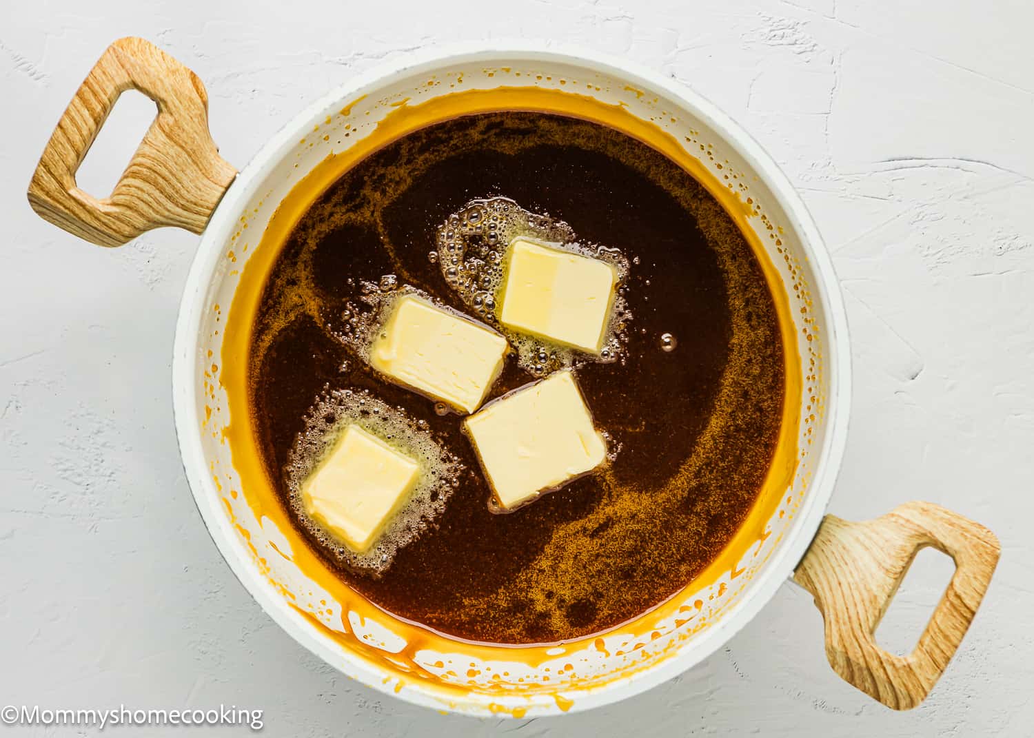 A pot of melted butter with buttery cubes.