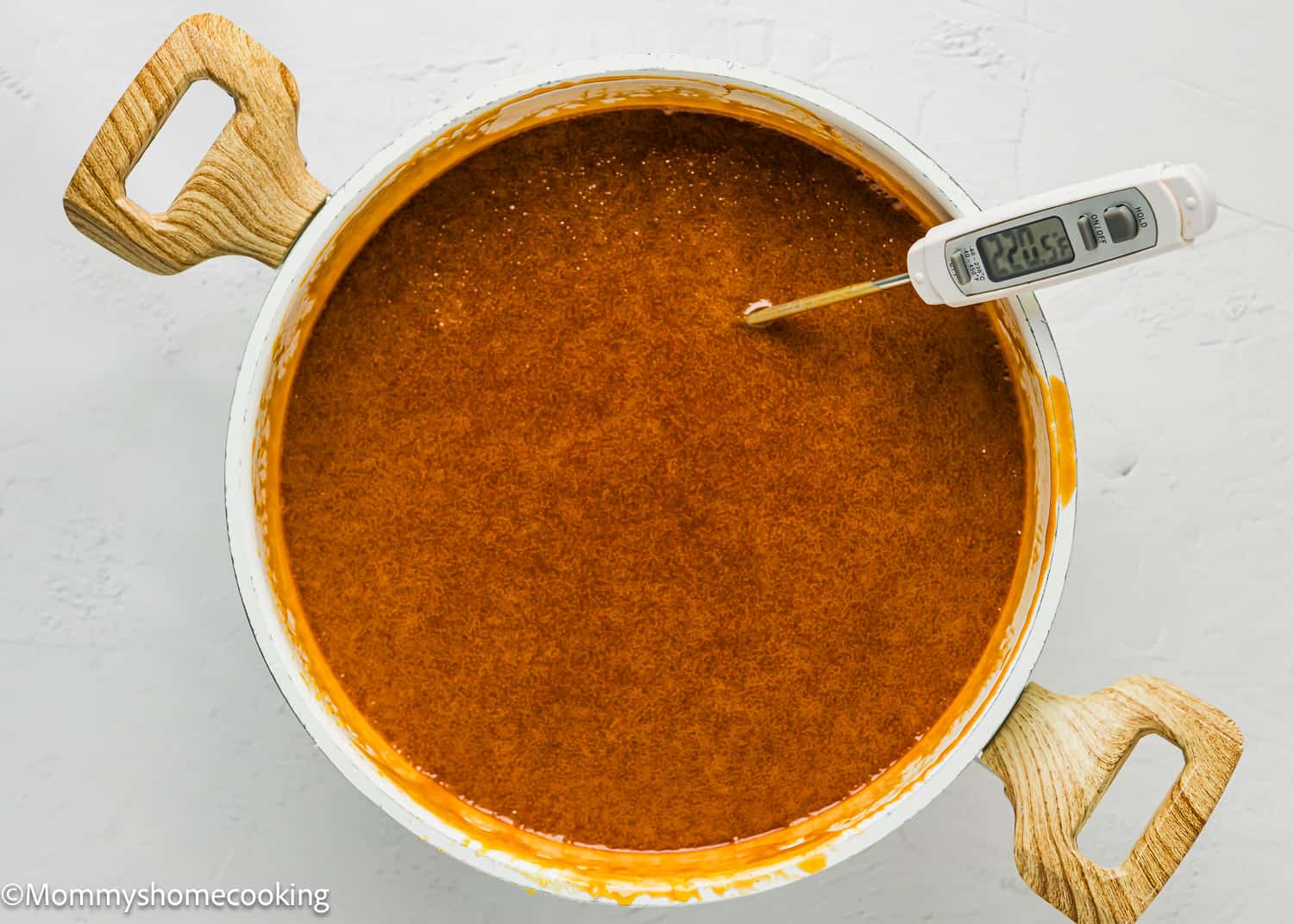 A pot with salted caramel with a thermometer in it.