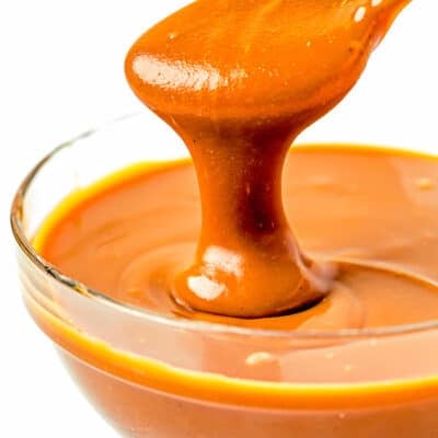 A spoon effortlessly pours salted caramel sauce into a bowl.