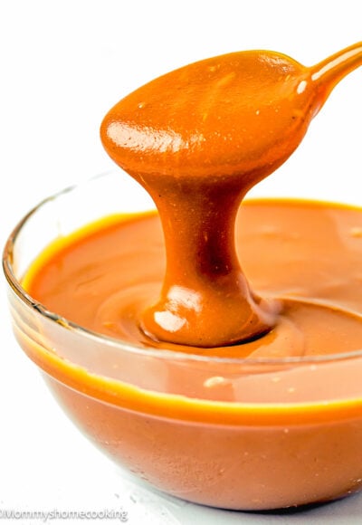 A spoon effortlessly pours salted caramel sauce into a bowl.