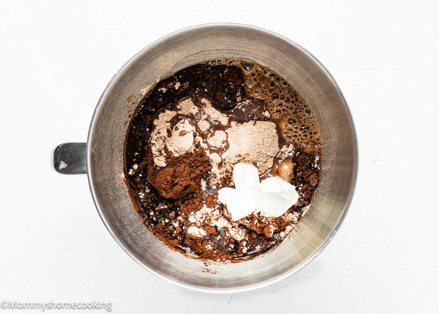 Ingredients in a metal bowl on a white background for boxed brownies made without eggs.