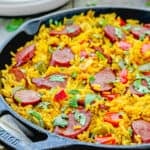 One Pot Sausage and Rice meal in a skillet over a wooden surface.