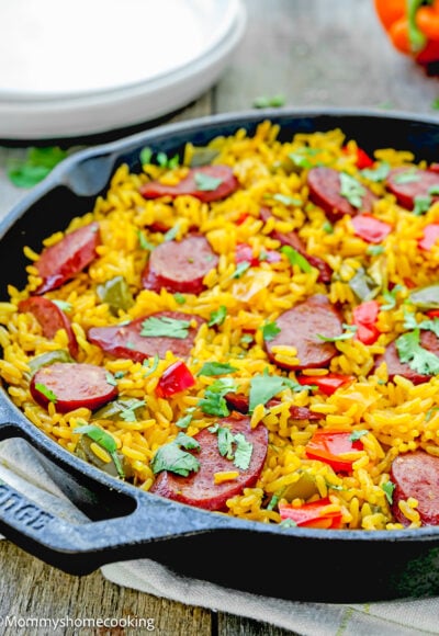 One Pot Sausage and Rice meal in a skillet over a wooden surface.