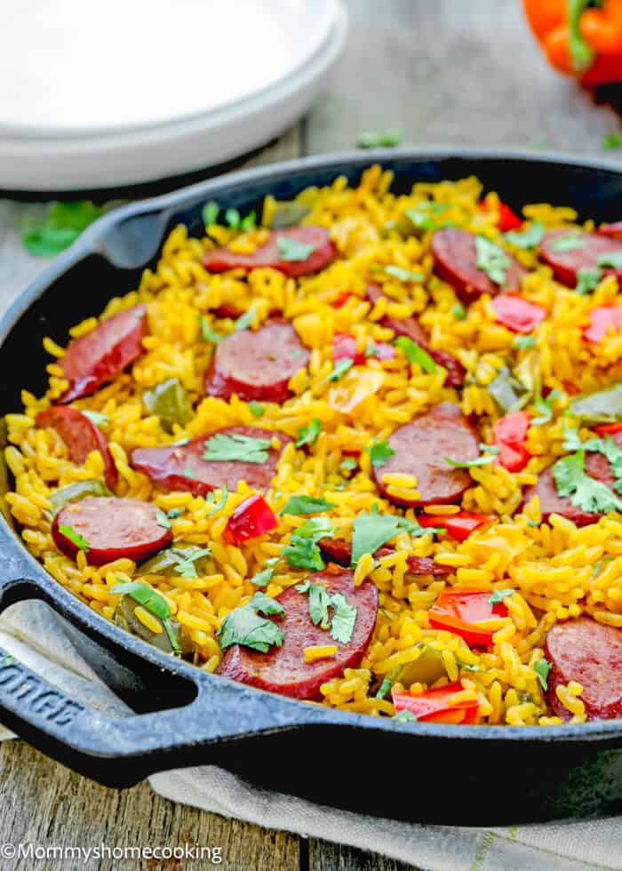 One Pot Sausage and Rice meal in a skillet over a wooden surface.