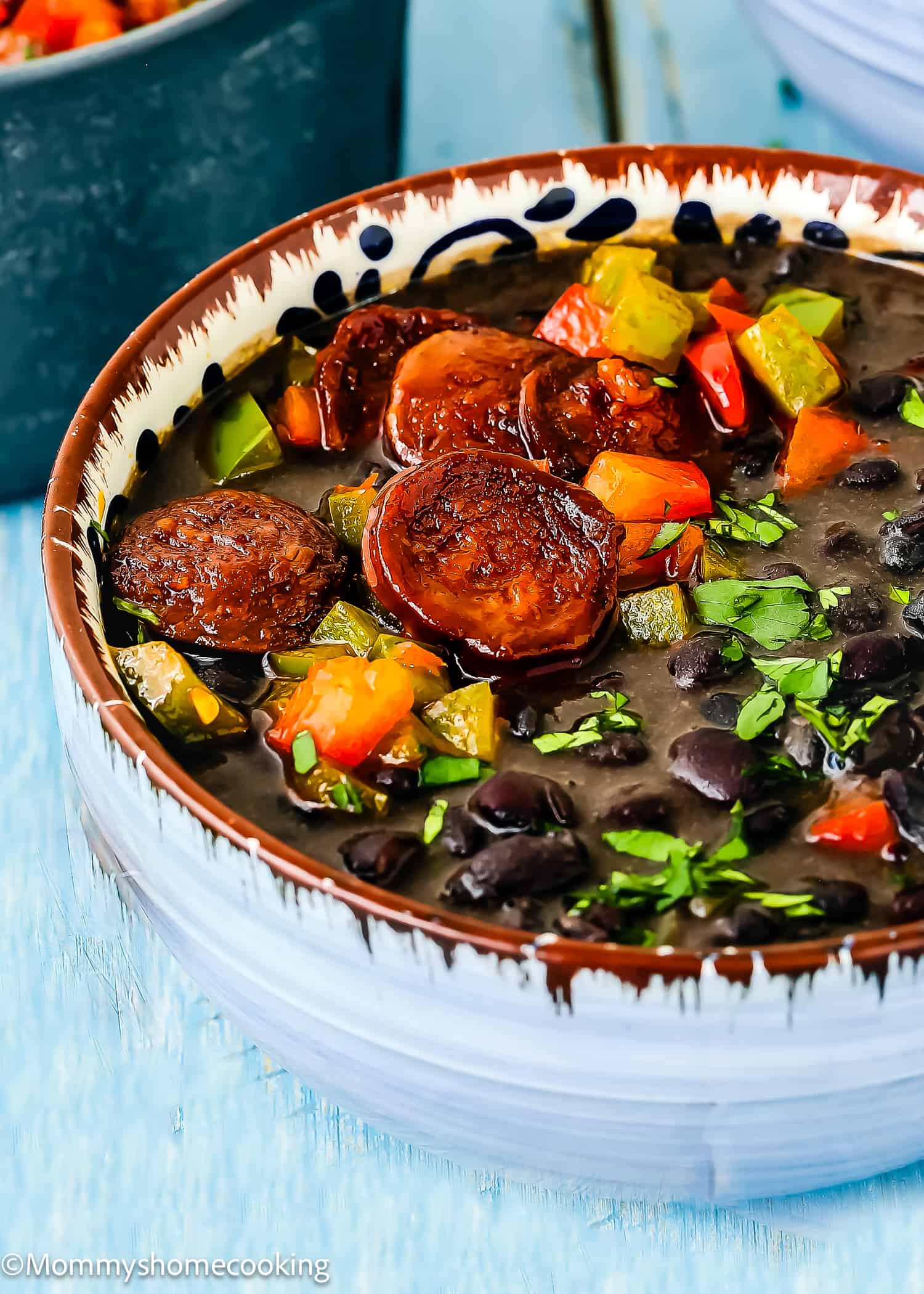 Venezuelan Black Bean Soup (Sopa de Caraotas) in a bowl over a blue surface. 
