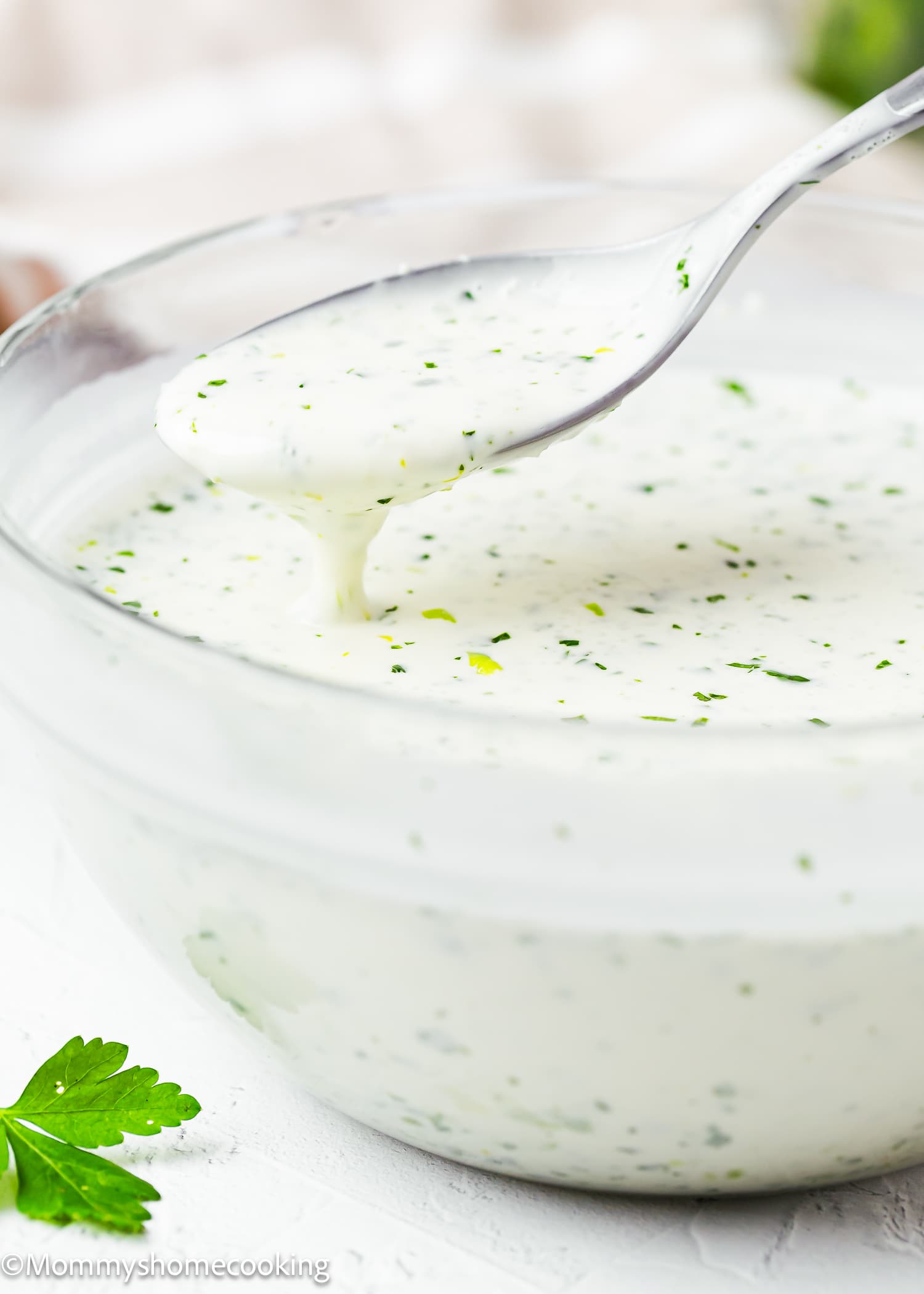 a spoon pouring Venezuelan Garlic Sauce (Salsa de Ajo Venezolana) in a glass bowl.