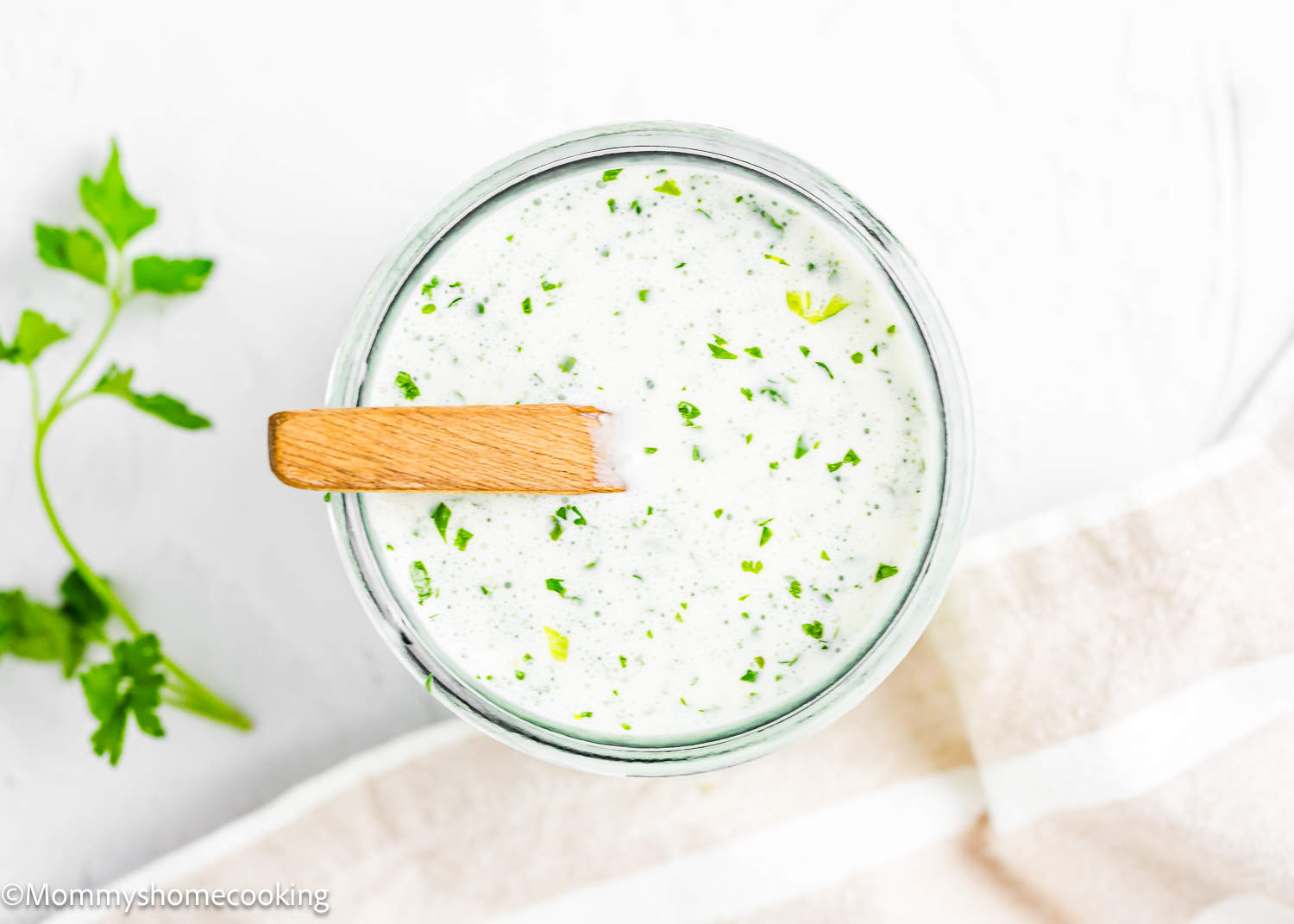 overhead view of Venezuelan Garlic Sauce (Salsa de Ajo Venezolana) in a glass container with a wooden.