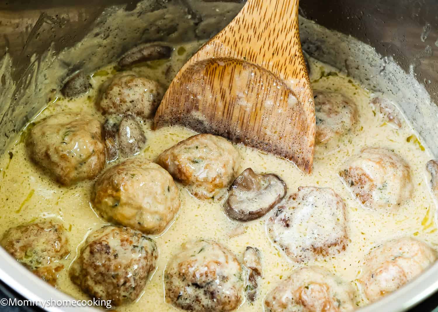 Stroganoff Meatballs in a pot with a wooden spoon.