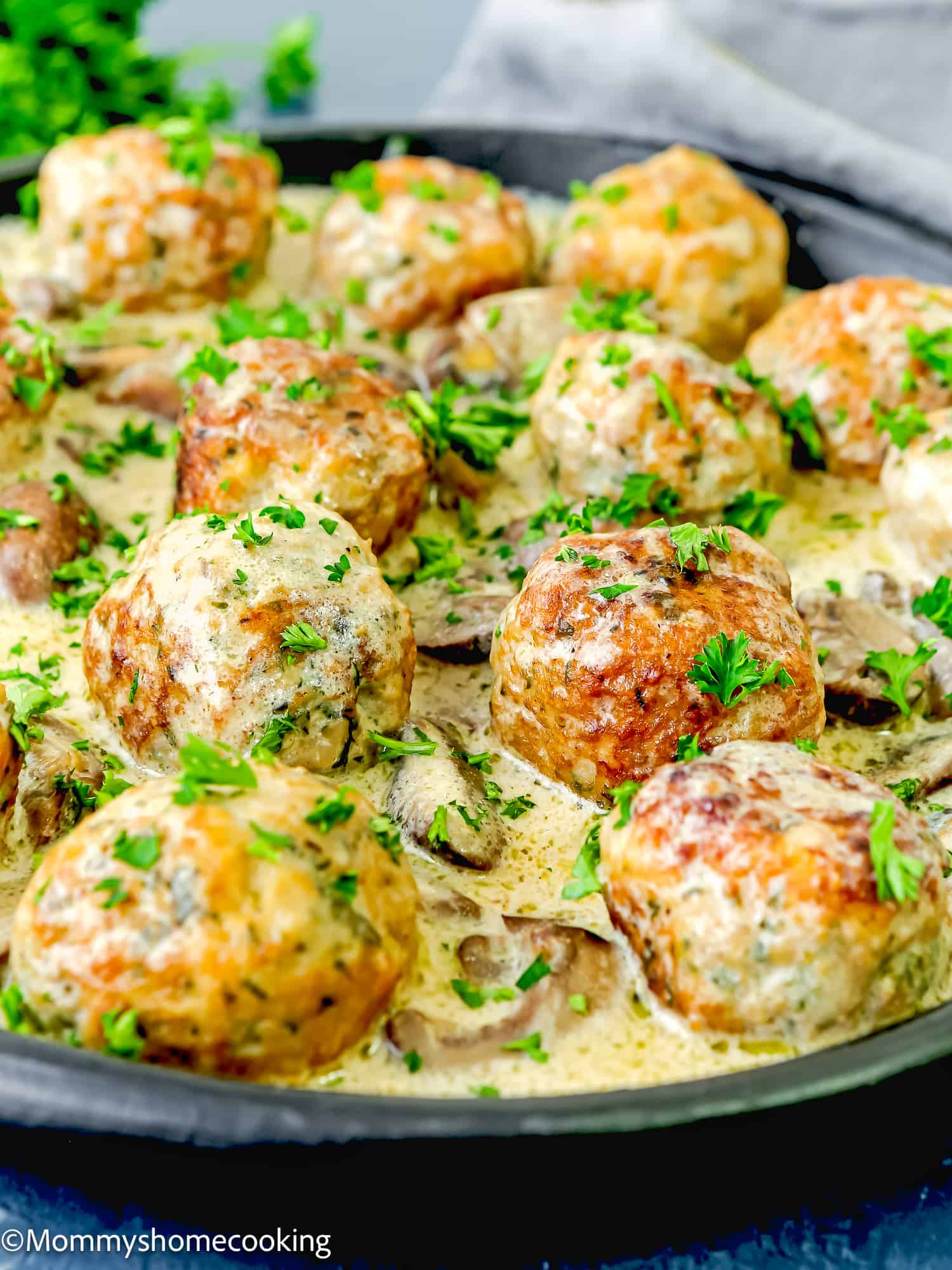 Stroganoff Meatballs with eggs with creamy sauce in a plate over a grey surface.