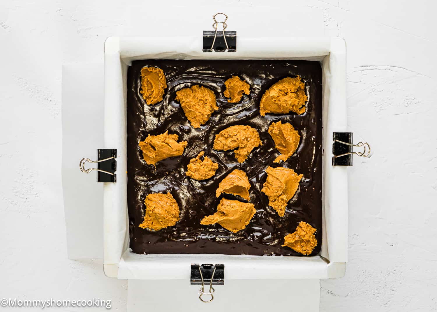 unbaked Brownies batter with cookie butter in a baking pan.