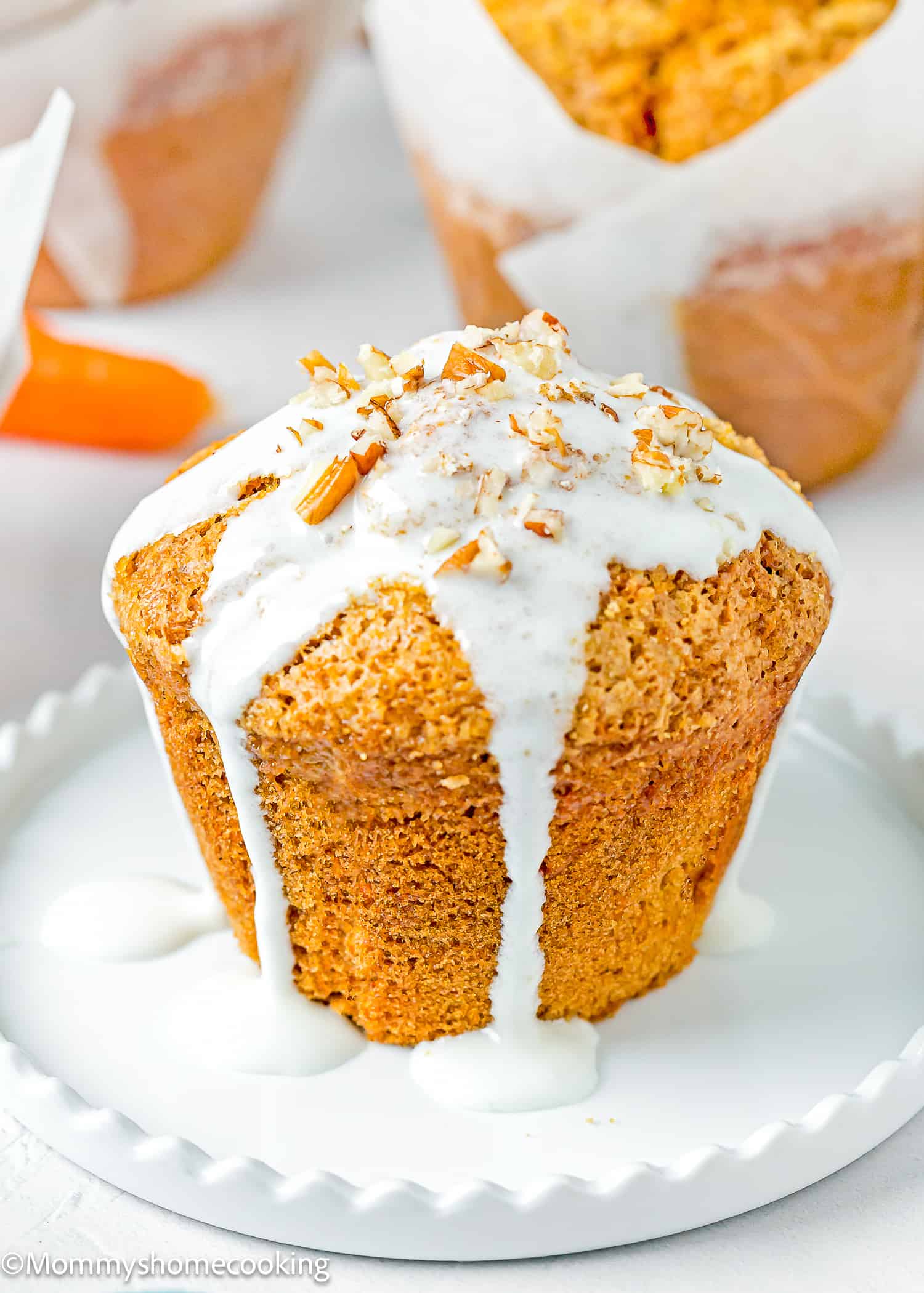 a Carrot Cake Muffin (No Eggs & No Dairy) with glaze and chopped pecans on a white plate.