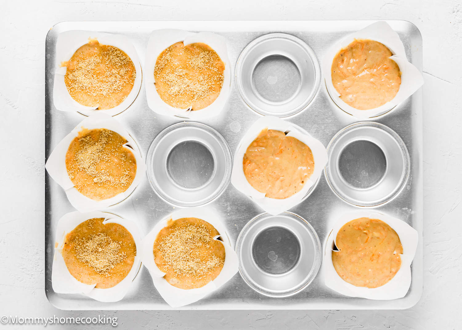 muffin pan with liner and dry ingredients for Carrot Cake Muffins (No Eggs & No Dairy) batter.