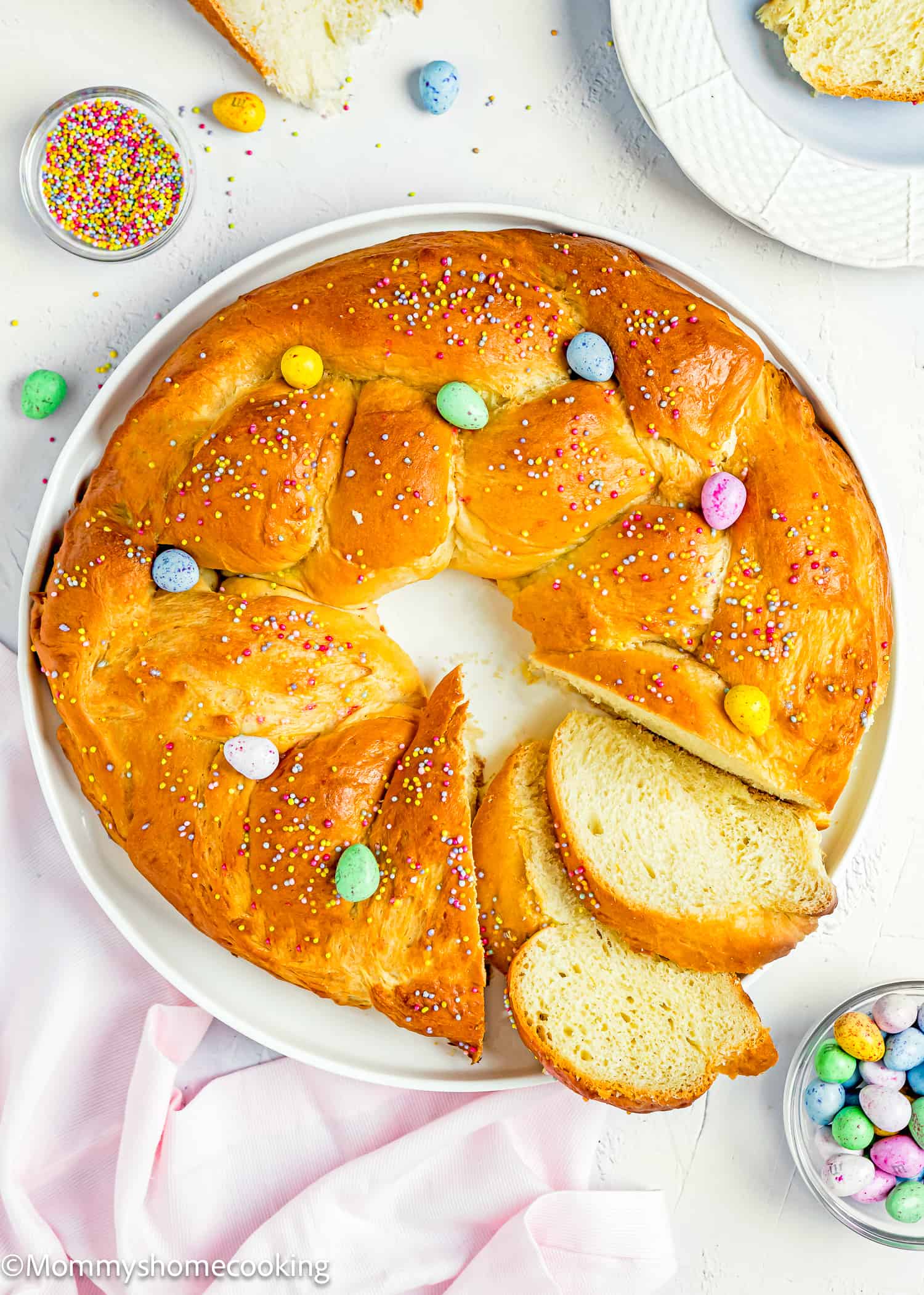 a sliced Easter Sweet Bread over a plate with sprinkles and easter chocolate mini eggs.