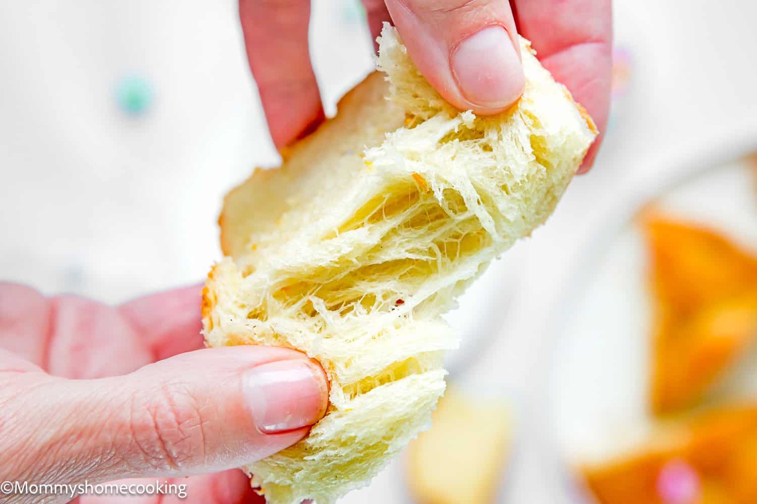 a hand pulling apart a slices of Easter Sweet Bread without eggs showing its perfect texture.