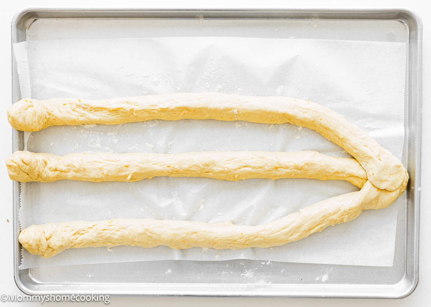 three ropes of unbaked Easter Sweet Bread dough over a baking tray.
