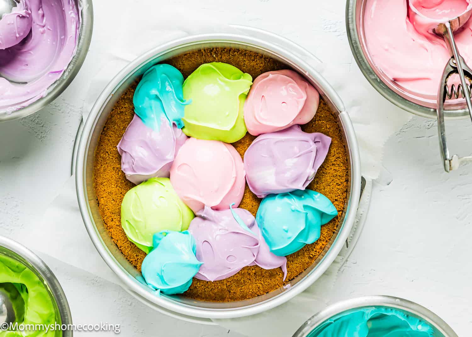 colourful spoonfuls of cheesecake batter in a springform pan.