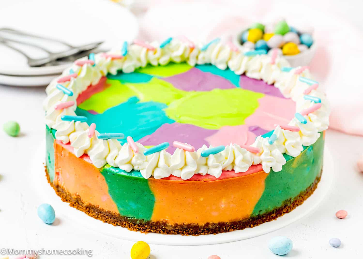whole Easy Baked Easter Cheesecake (Egg-free) over a white surface with chocolate eggs and sprinkles.