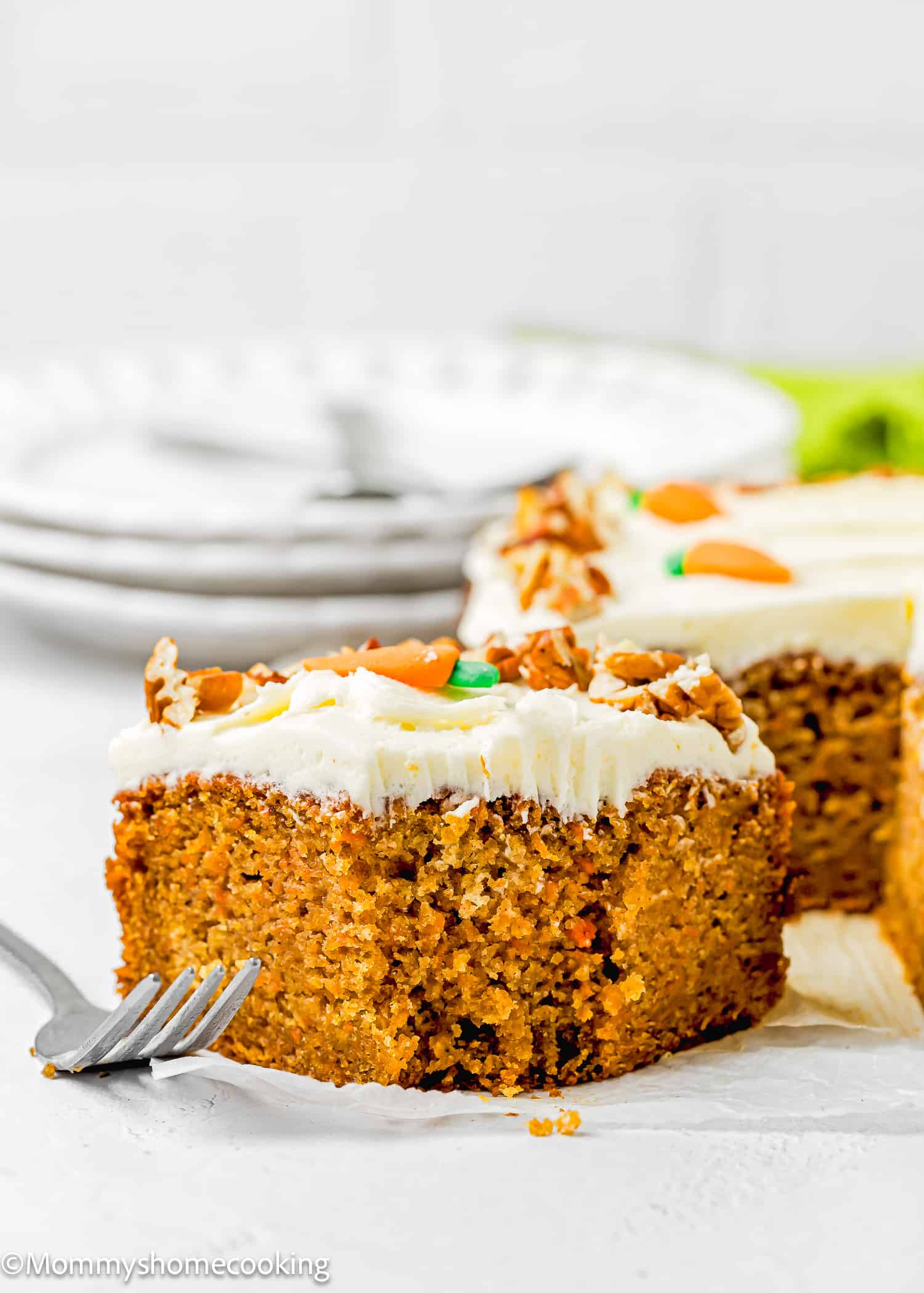 a bitten slice of Easy Carrot Cake Snack Cake (No Eggs – No Dairy) showing its moist and tender texture with plates and forks in the background.