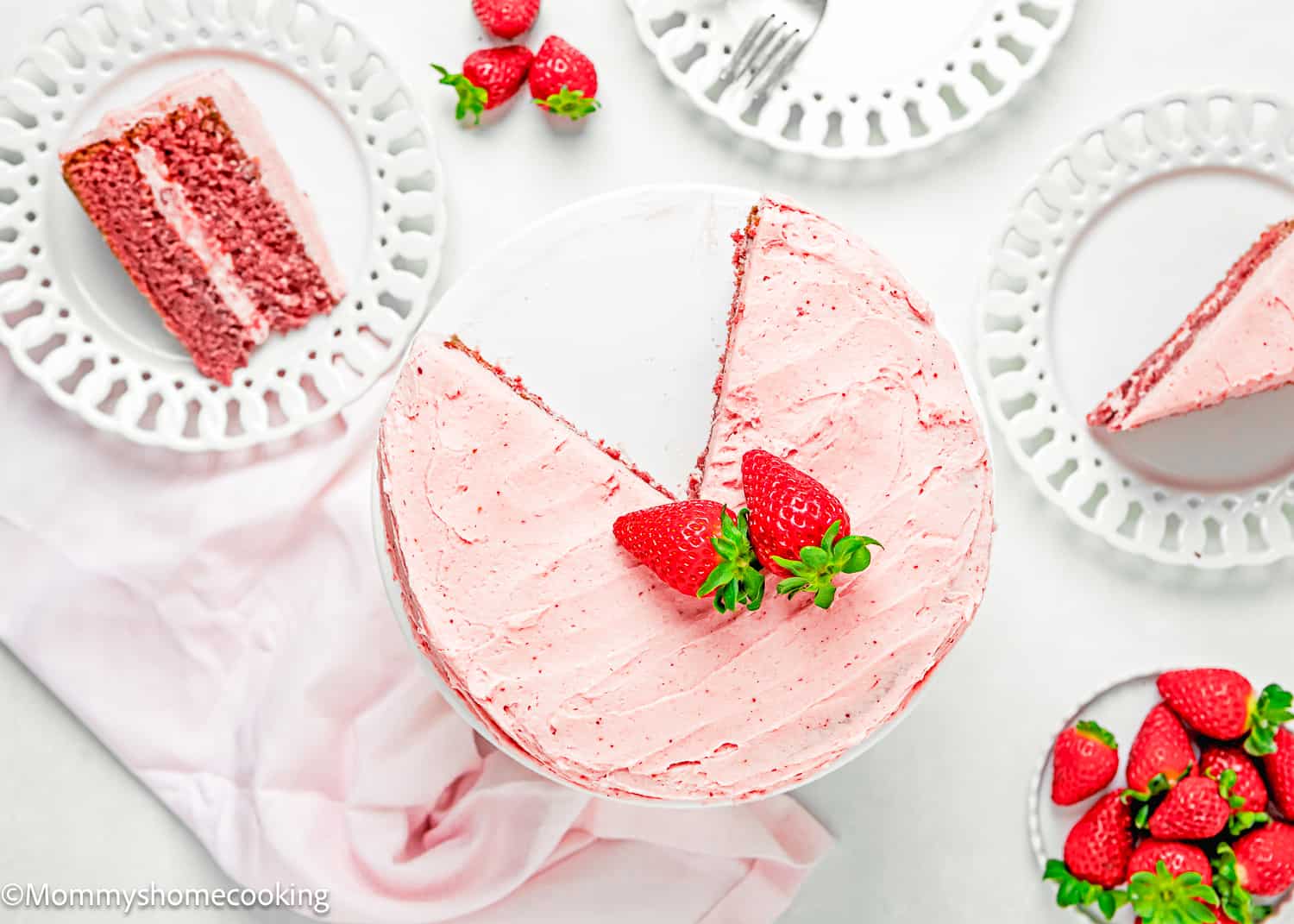 aEasy Fresh Strawberry Cake on a cake stand with plates with cake slices and fresh strawberries on the side.