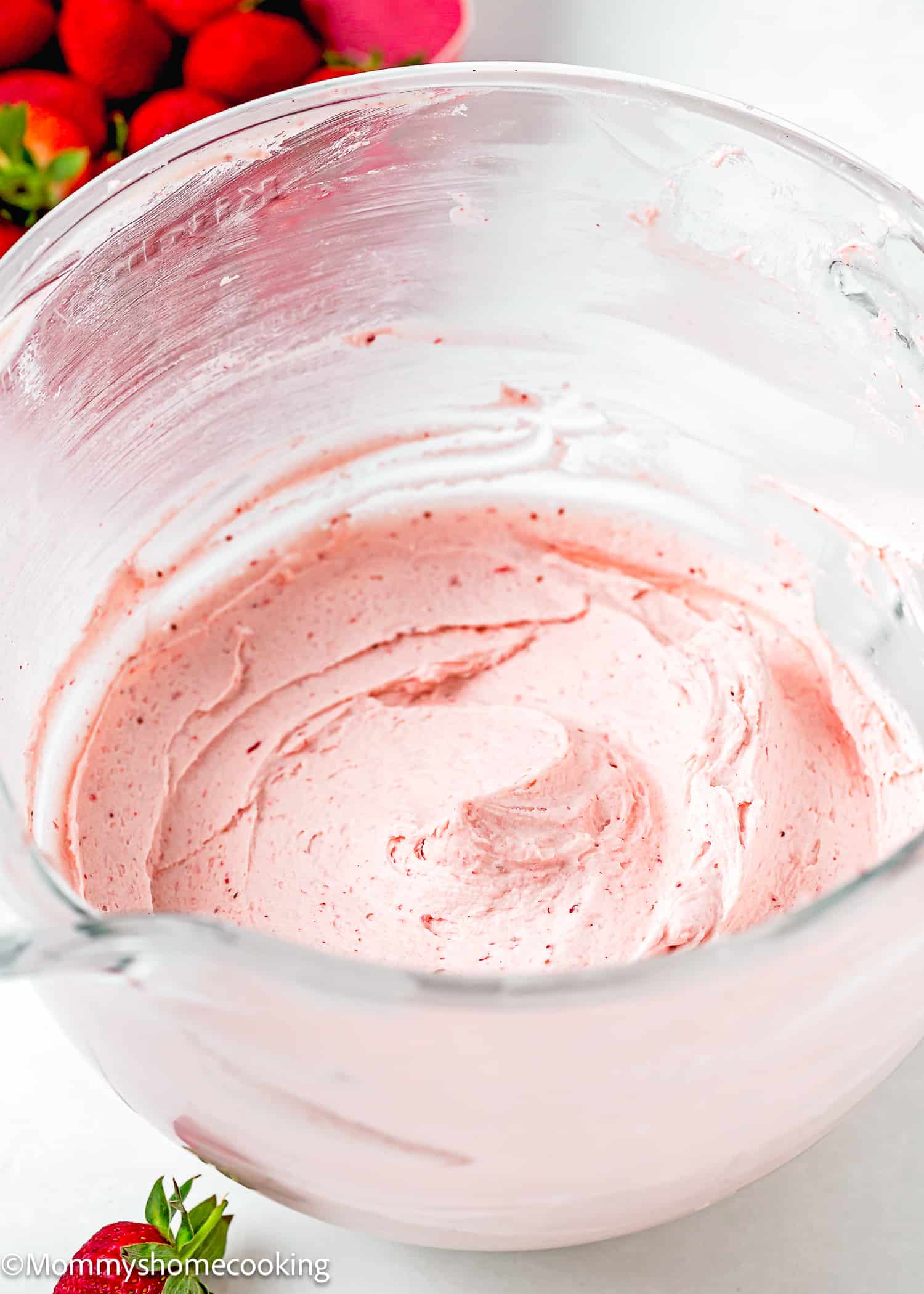 easy homemade strawberry frosting in a stand mixer bowl over a white surface with fresh strawberries on the side.