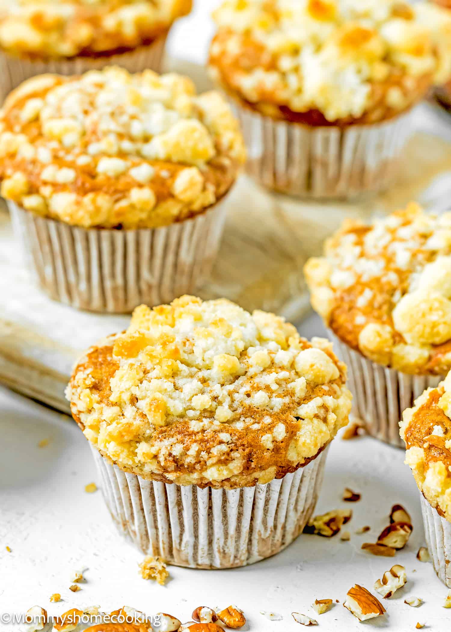 Hummingbird Muffins with crumb on top on a white surface with more muffins around.
