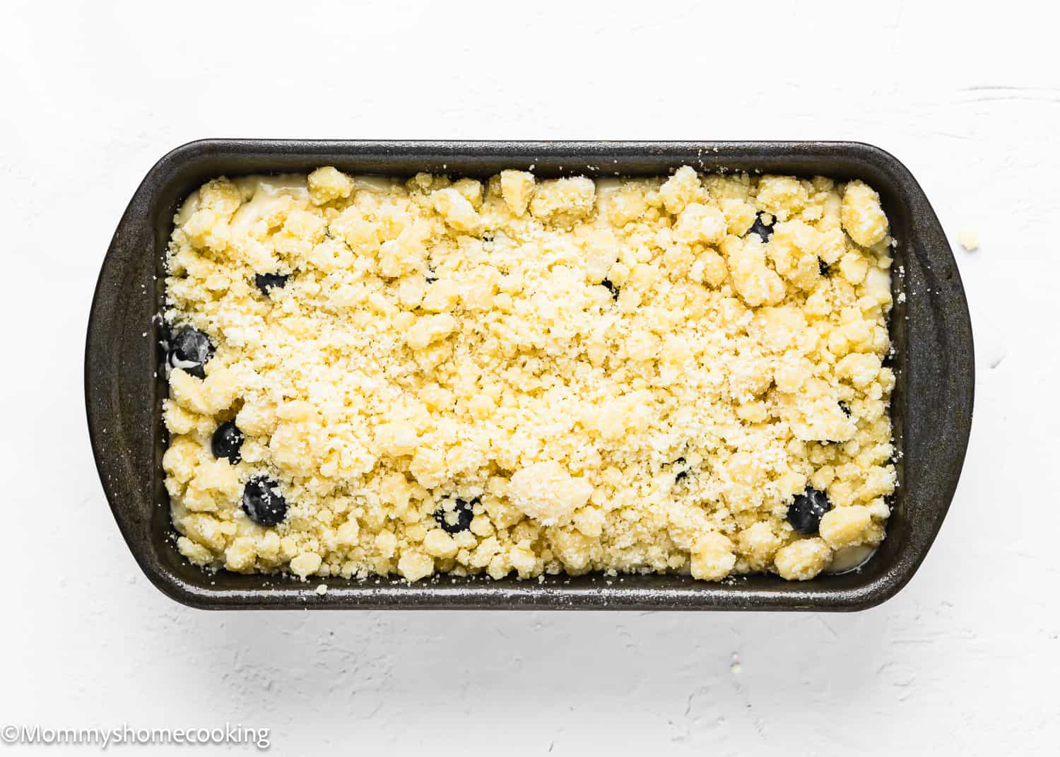 Eggless Lemon blueberry Loaf Cake batter with crumbs in a loaf pan.