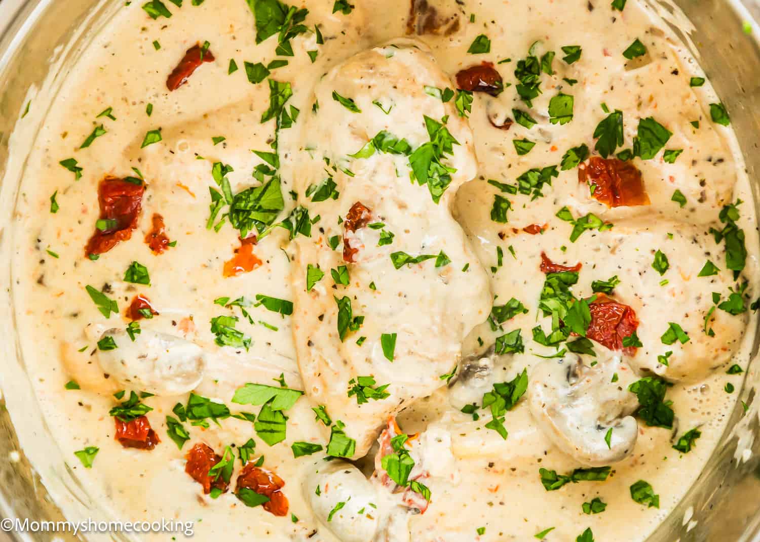 One Pan Creamy Chicken and Mushrooms garnished with chopped Parsley in a pot.