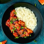 a black plate with homemade Super Easy Orange Chicken and rice.