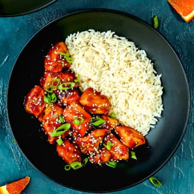 a black plate with homemade Super Easy Orange Chicken and rice.