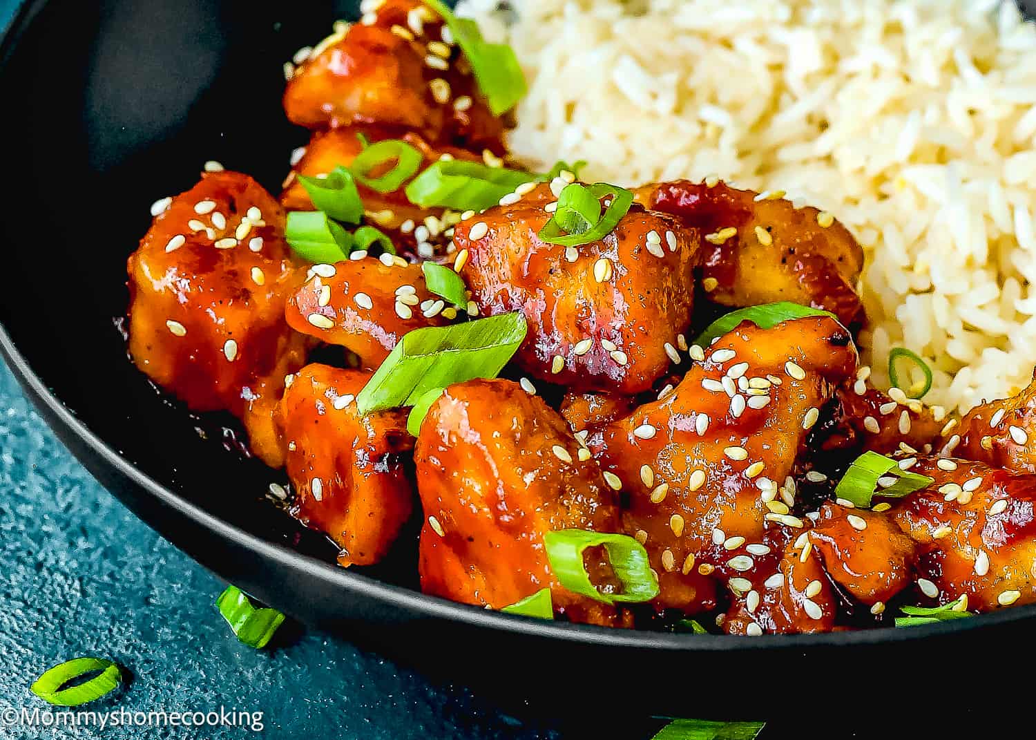 closeup of homemade Super Easy Orange Chicken and rice in a black plate.