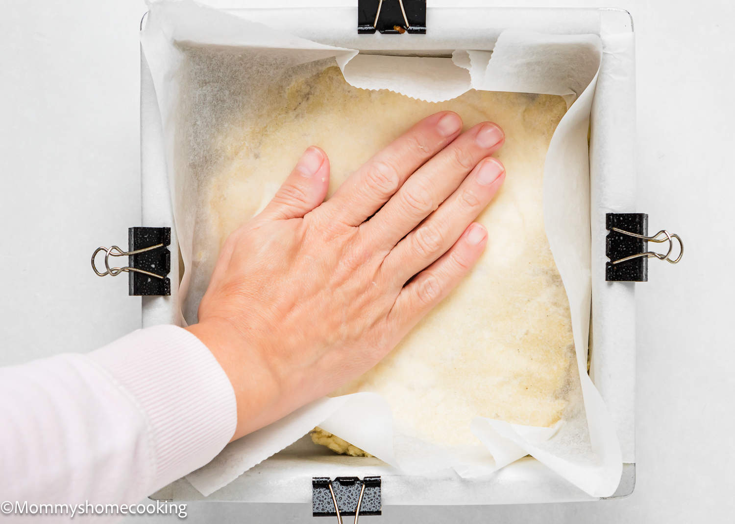 a woman hand spreading egg-free sugar cookie dough into a baking pan.