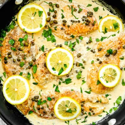 Easy Chicken Piccata in creamy sauce in a skilled over a wooden surface.