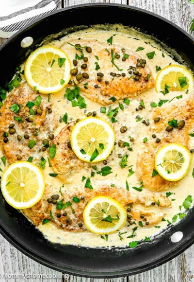 Easy Chicken Piccata in creamy sauce in a skilled over a wooden surface.