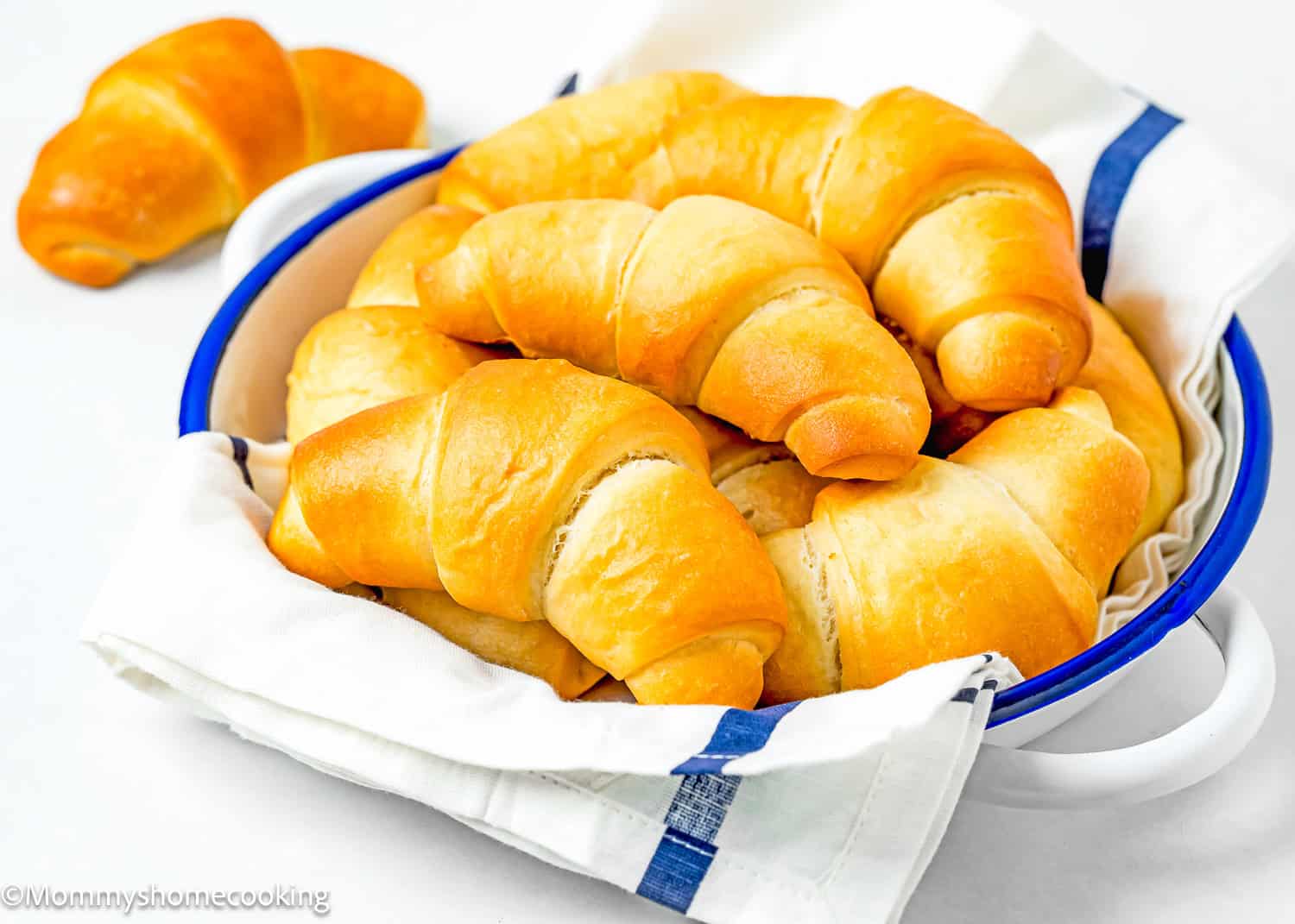 Homemade Egg-free Crescents Rolls in a bread basket with a kitchen towel.