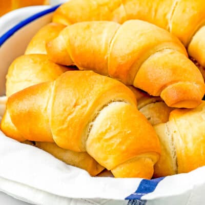 Homemade Eggless Crescents Rolls in a bread basket with a kitchen towel.