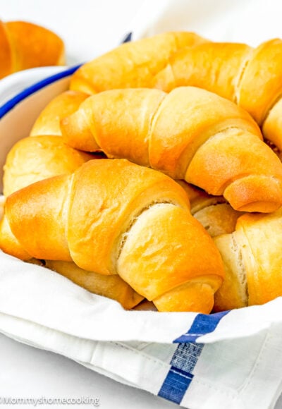 Homemade Eggless Crescents Rolls in a bread basket with a kitchen towel.