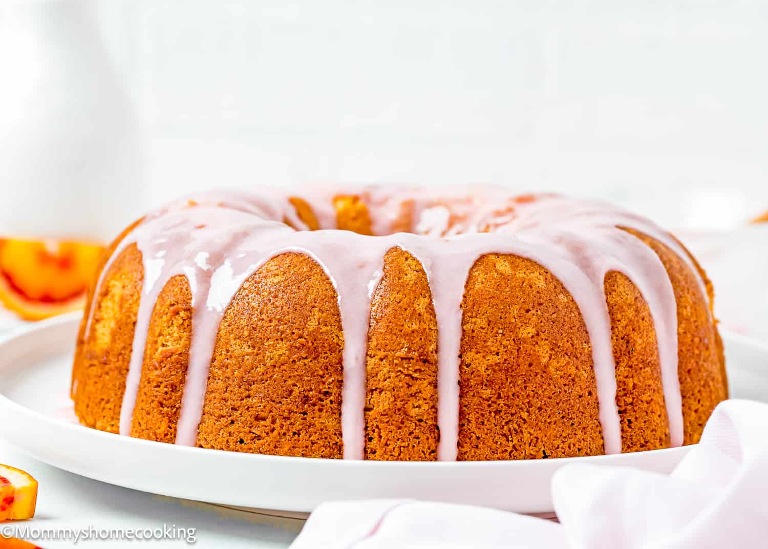 a whole Simple Orange Bundt Cake without eggs with glaze on a serving plate.